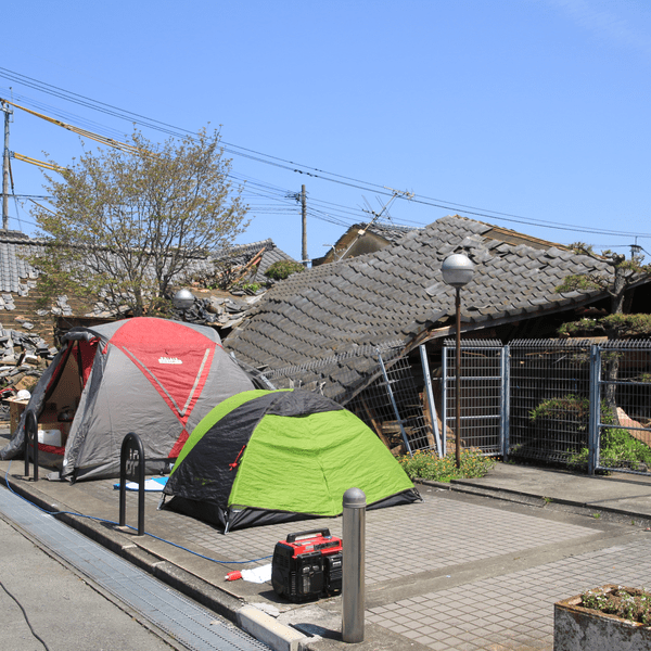地震で倒壊した建物とテントの画像